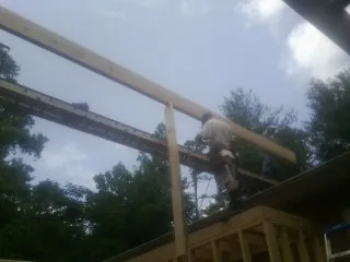 Carpenter setting a ridge beam over a new addition frame — Ice Dam Removal by Roofing Brothers in Normangee