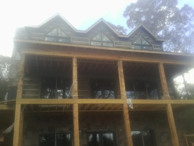 Dormers and porch framing on a large log home under construction — Roof Coating work by our crew in Normangee