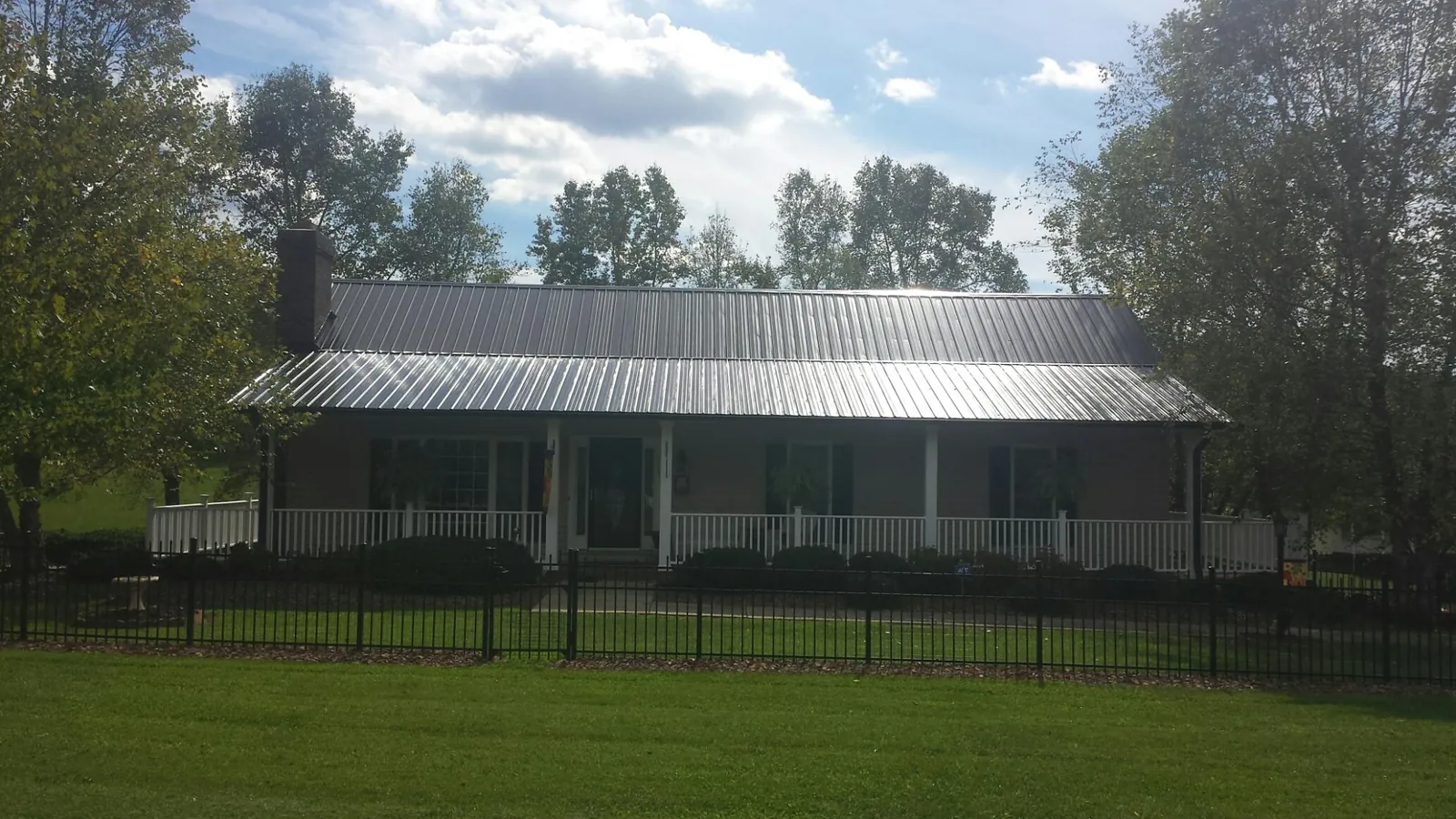Gray metal roof on a brick ranch with a full width front porch — Gutter Guard Installation work by our crew in Normangee