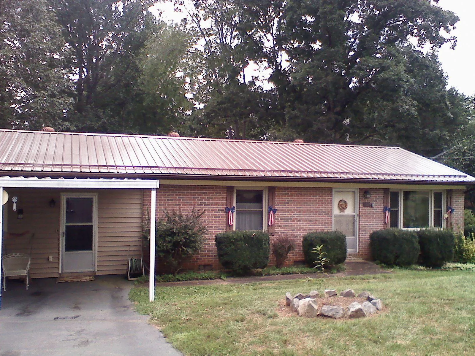 Bronze metal roof and carport on a brick ranch home — Roof Repair work by our crew in Normangee