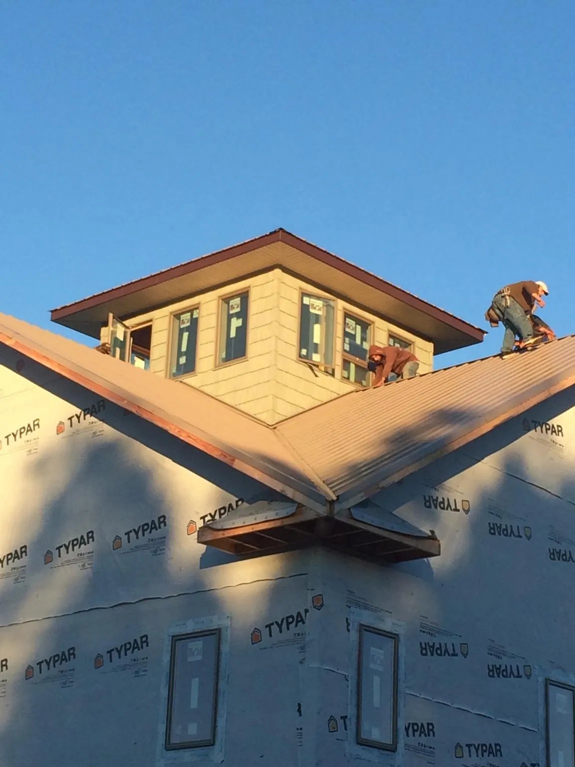 Roofers working around a rooftop cupola on a new metal roof at sunset — Roof Waterproofing in Normangee by Roofing Brothers
